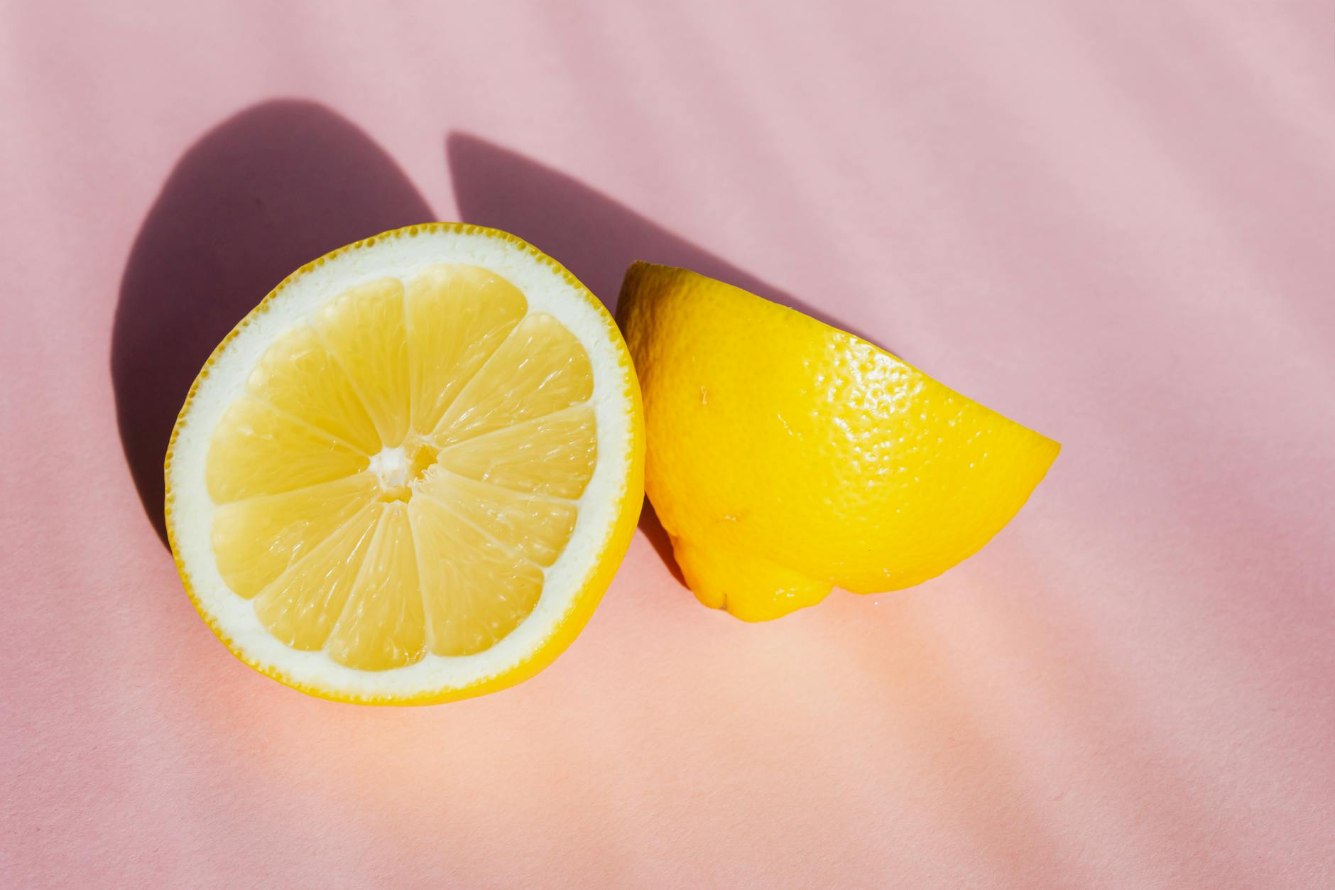 Fresh lemon halves on a pink background in natural sunlight