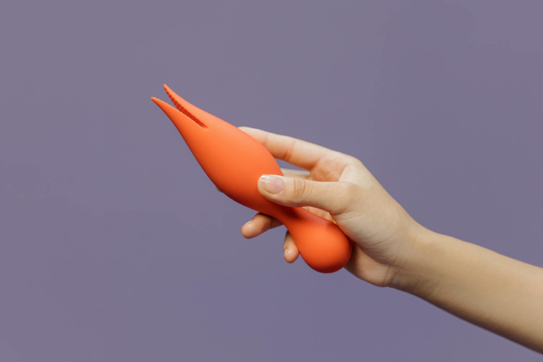 A hand holding a lemon-colored vibrator against a minimalistic purple backdrop, symbolizing renewed intimacy and sensual reconnection.