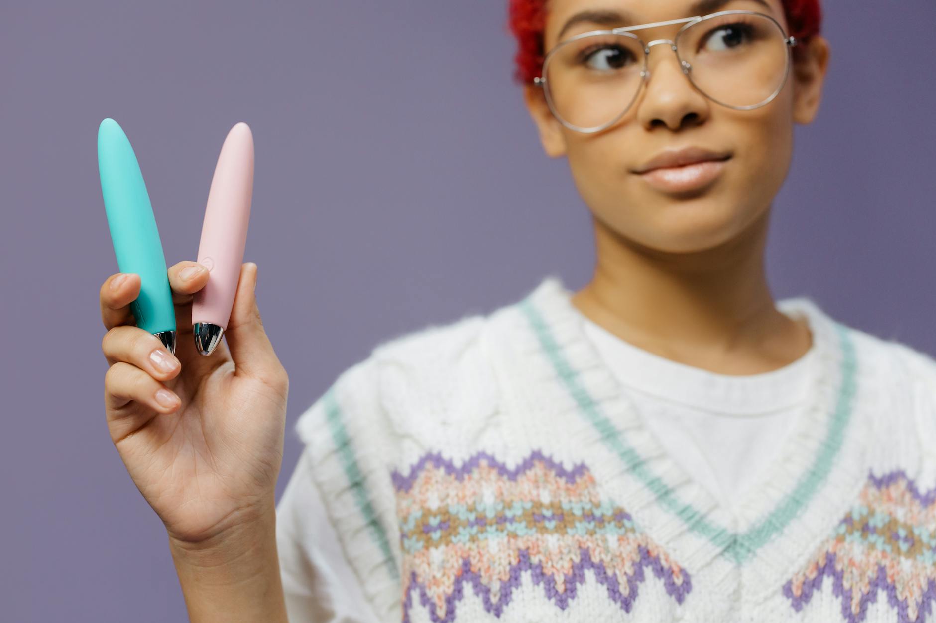 Eine blaue Silikonmassager in der Hand vor lila Hintergrund, symbolisiert Selbstliebe und weibliche Sexualität