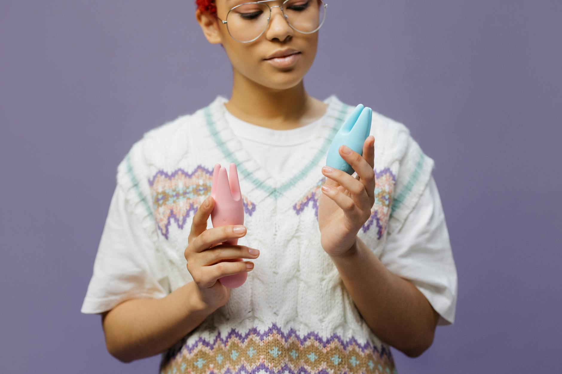 A lemon clitoral vibrator held in hand against a soft purple background, showing color and form of the device.